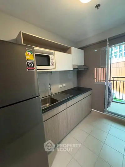 Modern kitchen with sleek cabinetry and balcony access in urban apartment