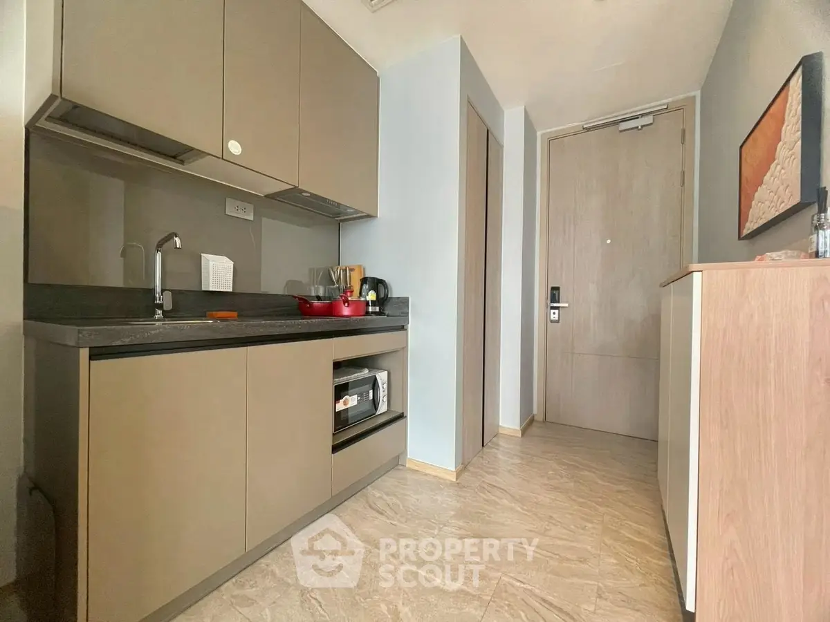 Modern compact kitchen with sleek cabinetry and integrated appliances in a stylish apartment.
