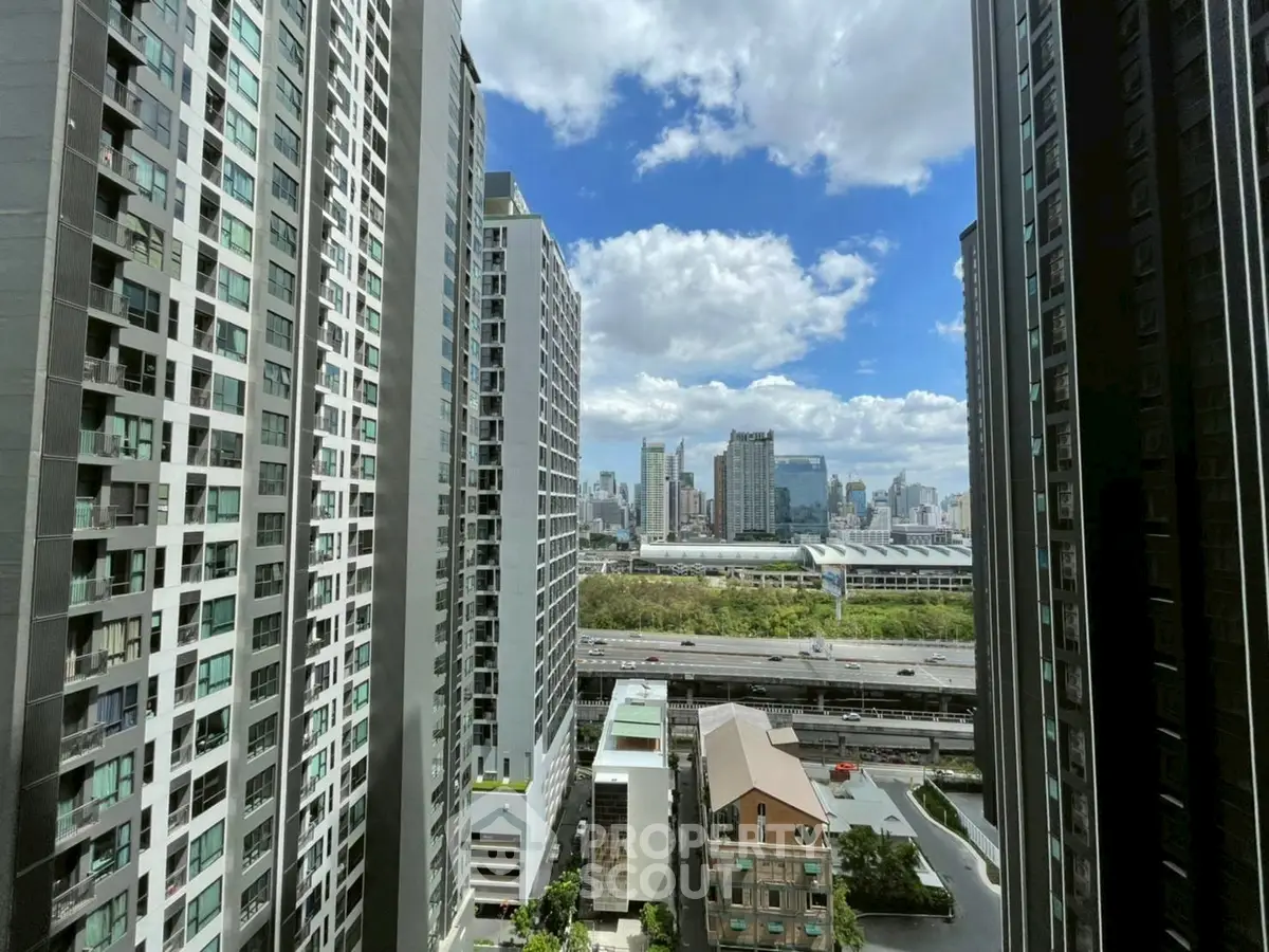 Stunning cityscape view from high-rise apartment balcony with clear blue skies.