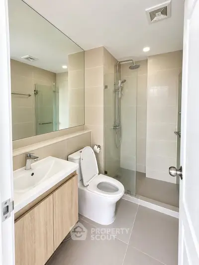 Modern bathroom with glass shower and sleek fixtures in contemporary apartment.