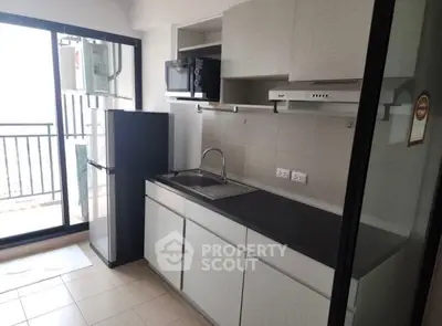 Modern kitchen with balcony view, featuring sleek cabinetry and compact appliances.