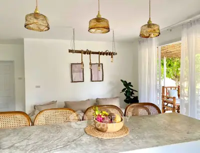 Chic modern kitchen with open layout and stylish lighting, featuring a cozy dining area and lush garden view.