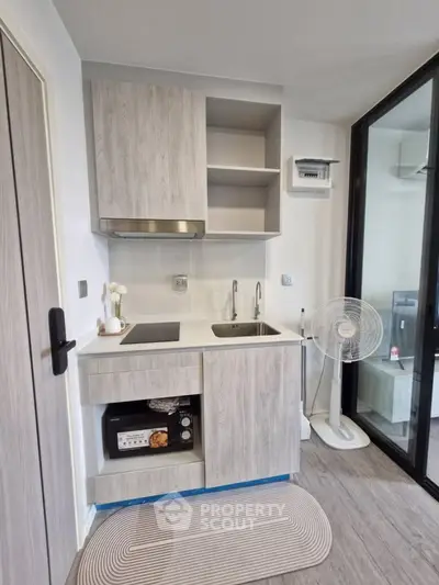 Modern compact kitchen with sleek cabinetry and appliances in a stylish apartment.