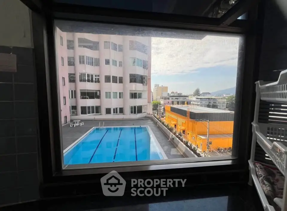 Stunning pool view from a modern apartment window, showcasing urban living with leisure amenities.