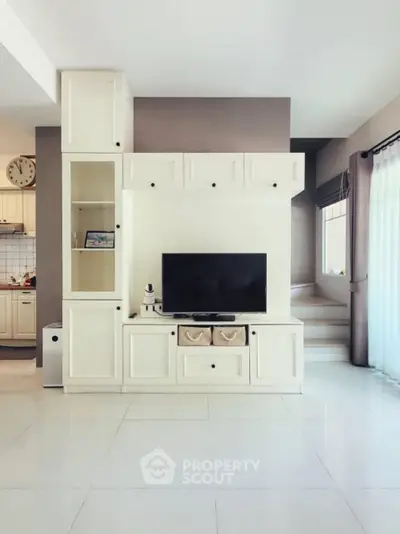 Spacious living room with modern entertainment center and natural light