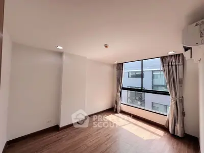 Bright and spacious room with large window and wooden flooring