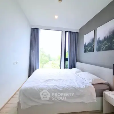 Bright and cozy bedroom with large window and modern decor in a serene setting.