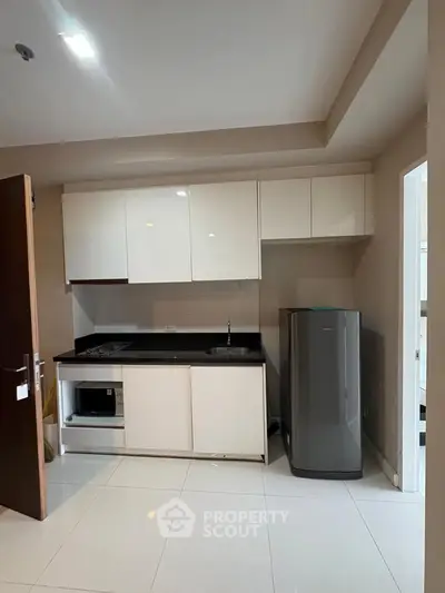 Modern kitchen with sleek cabinets, fridge, and built-in stove in a compact layout.