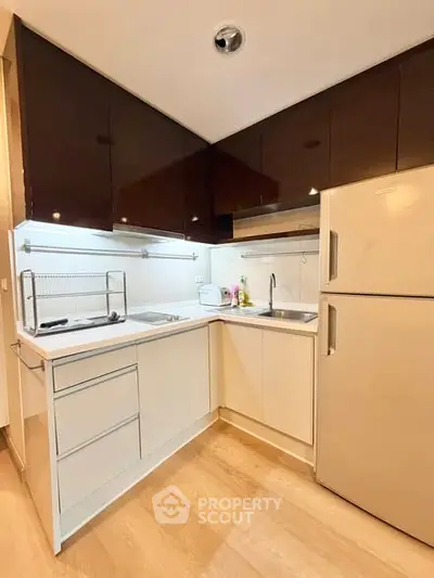 Modern kitchen with sleek cabinetry and stainless steel fridge in a cozy apartment.