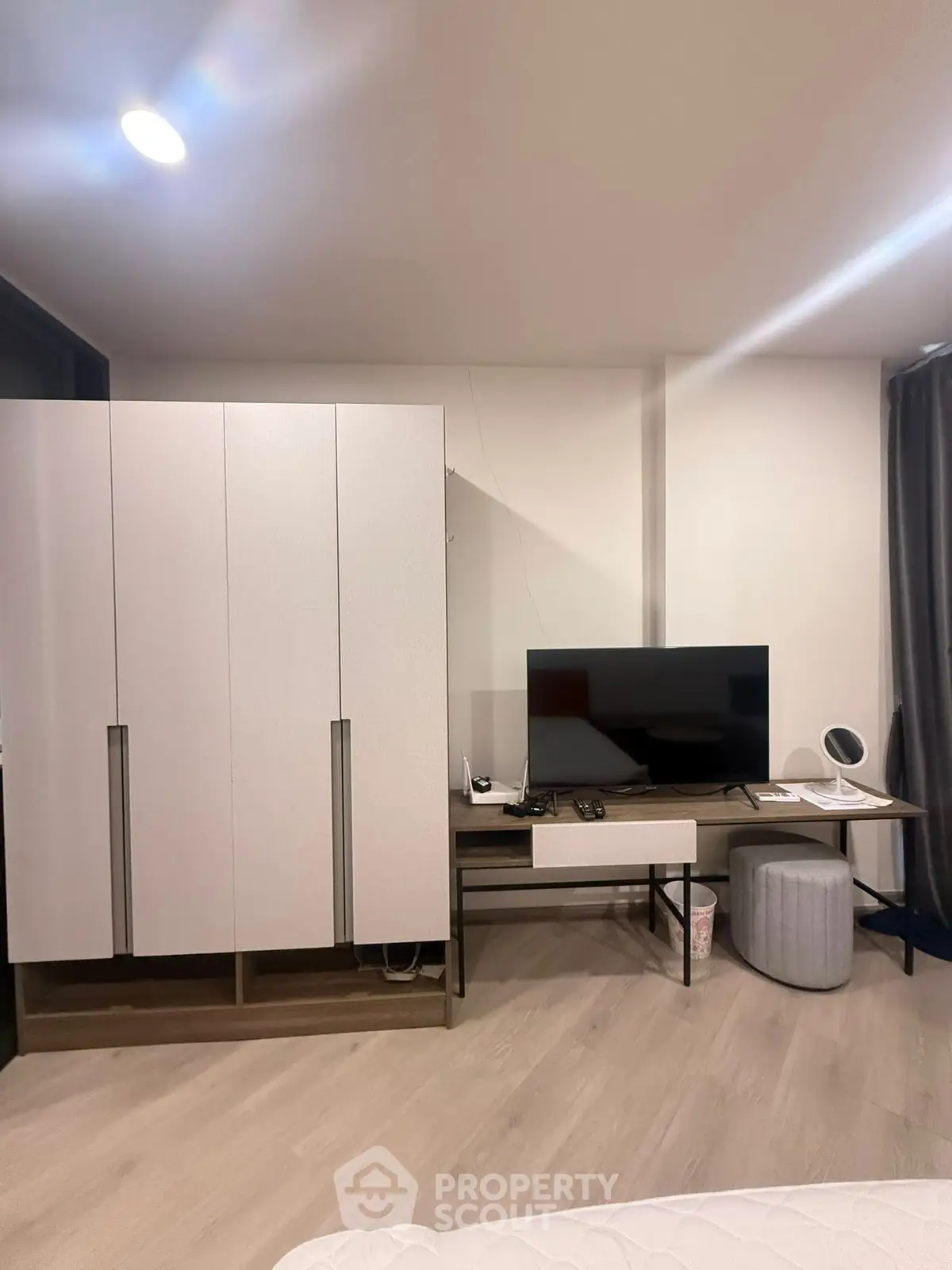 Modern bedroom with sleek wardrobe and flat-screen TV, perfect for contemporary living.