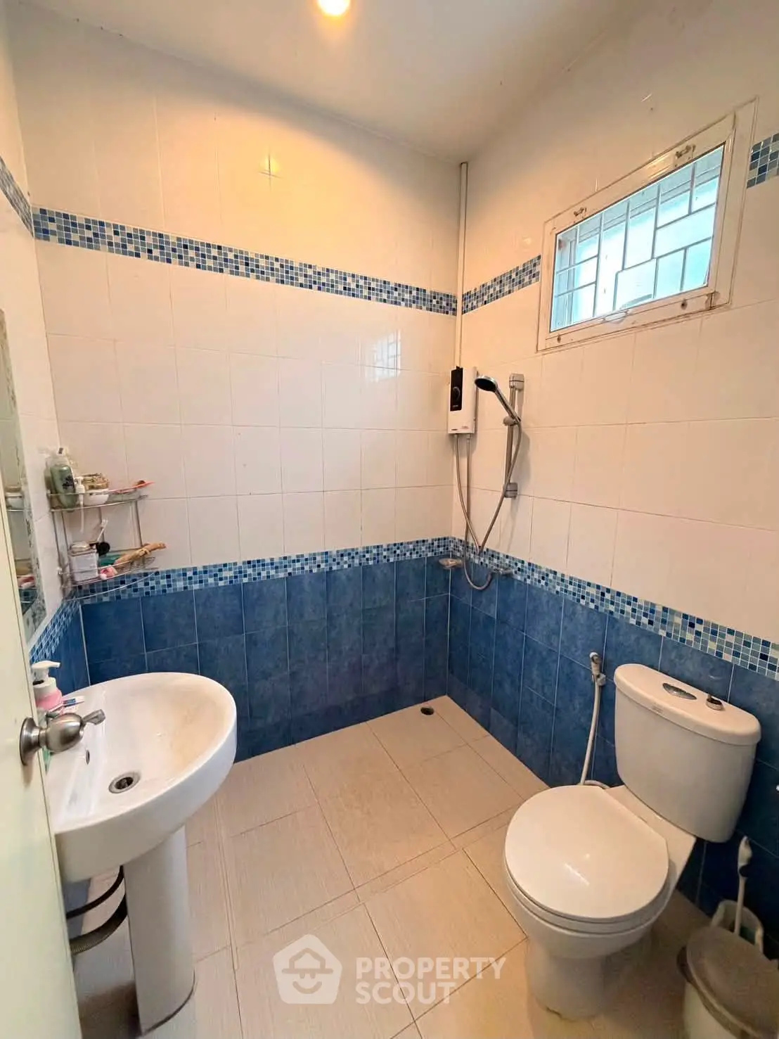 Modern bathroom with blue and white tiles, featuring a shower and toilet in a compact layout.