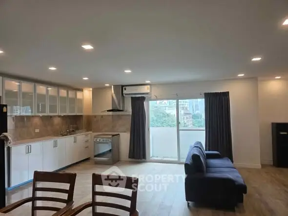 Spacious modern living room with open kitchen and balcony view.