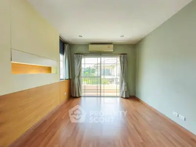 Spacious empty room with wooden flooring and balcony view, perfect for customization.