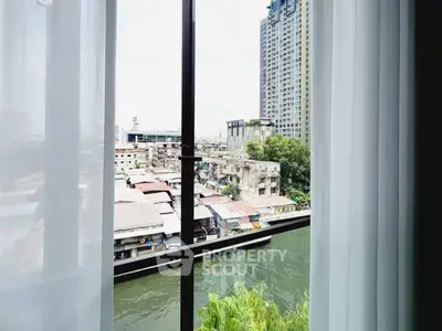 Stunning urban view from high-rise apartment window overlooking river and cityscape.
