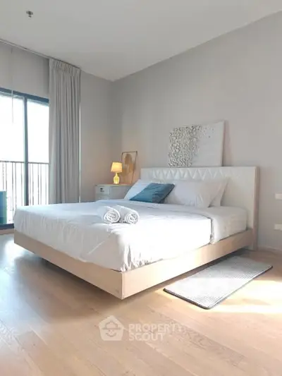 Spacious and bright bedroom with modern decor and large window for natural light.