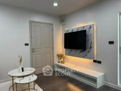 Modern living room with stylish TV setup and elegant marble tables.