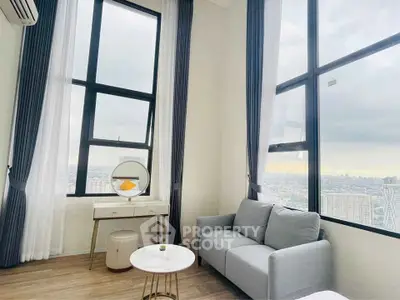 Modern living room with large windows and city view, featuring a cozy sofa and stylish decor.