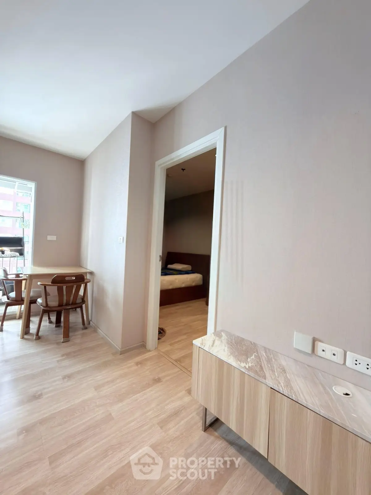 Modern apartment interior with wooden flooring and stylish furniture, featuring a cozy dining area and a glimpse of the bedroom.