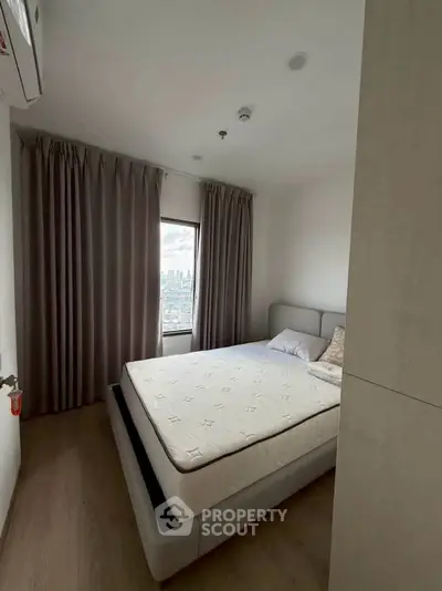Cozy bedroom with city view, featuring a comfortable bed and elegant curtains, perfect for relaxation.