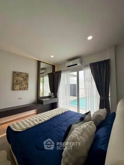Luxurious bedroom with pool view, modern decor, and ample natural light.