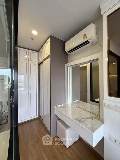 Modern bedroom with built-in wardrobe and air conditioning, featuring a sleek vanity area and wooden flooring.