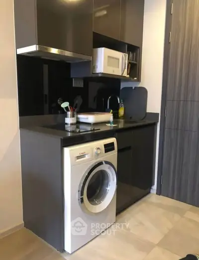 Modern kitchen with sleek cabinetry and built-in appliances including washing machine and microwave.