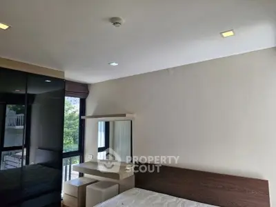 Modern bedroom with sleek furniture and large window offering natural light.