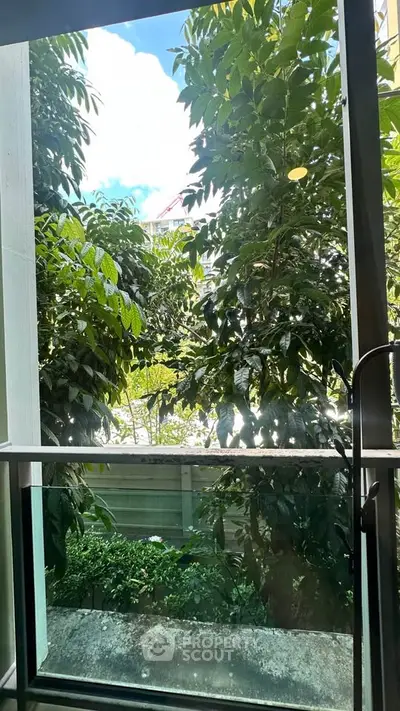 Lush garden view from a modern balcony with glass railing