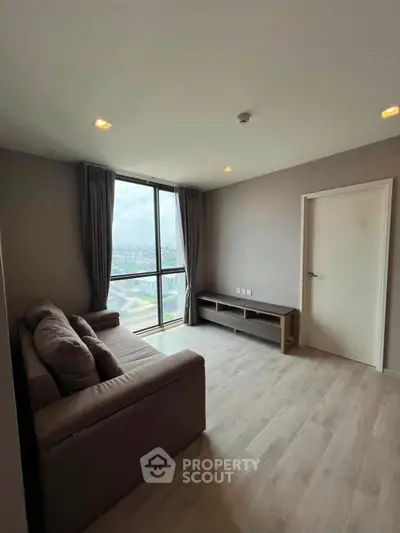 Modern living room with large window and city view, featuring a cozy sofa and sleek flooring.