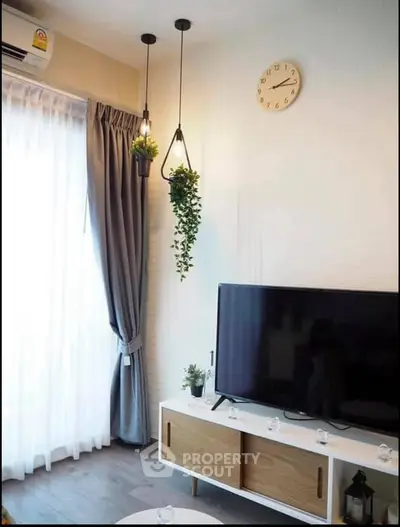 Modern living room with stylish decor, large TV, and natural light from floor-to-ceiling window.