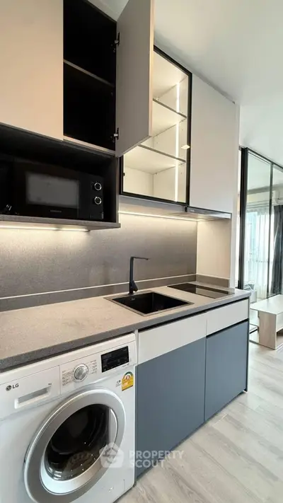Modern kitchen with sleek cabinetry, built-in microwave, and washing machine in a stylish apartment.