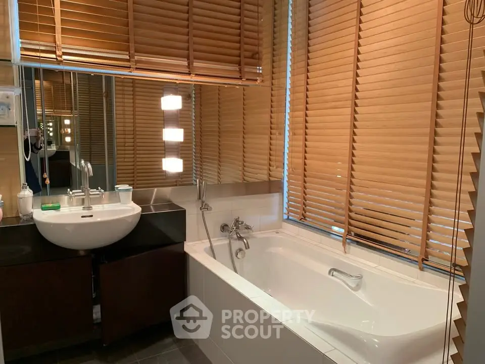 Modern bathroom with sleek design featuring a bathtub and stylish blinds.