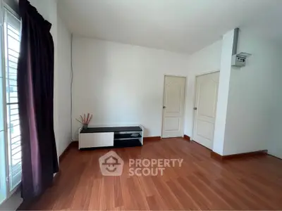 Spacious empty room with wooden flooring and modern TV stand