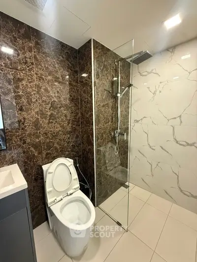 Luxurious modern bathroom with marble tiles and glass shower enclosure