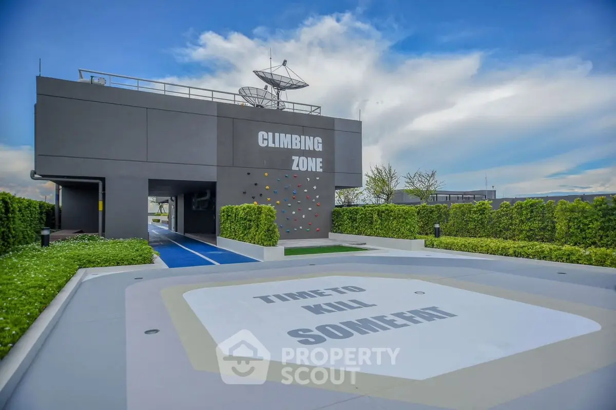 Modern rooftop climbing zone with lush greenery and clear blue sky.