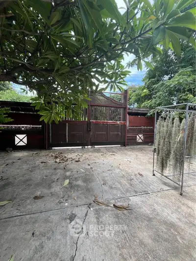 Charming outdoor space with lush greenery and rustic wooden gate, perfect for relaxation and privacy.
