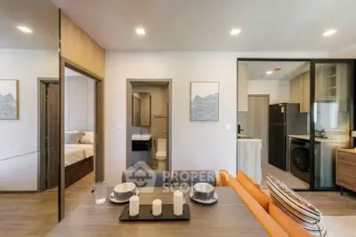 Modern open-plan living and dining area with stylish kitchen and cozy bedroom view.