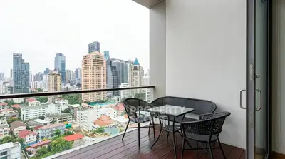 Stunning city view from a modern balcony with stylish outdoor seating.