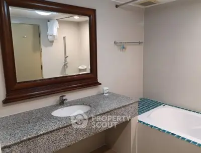 Spacious bathroom with granite countertop and bathtub in modern apartment.