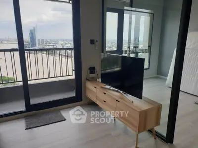 Modern living room with balcony and city view, featuring sleek TV stand and glass partition.