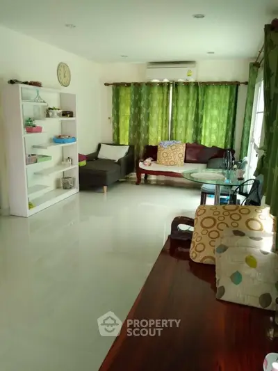 Spacious living room with modern decor and green curtains, perfect for relaxation and entertaining.