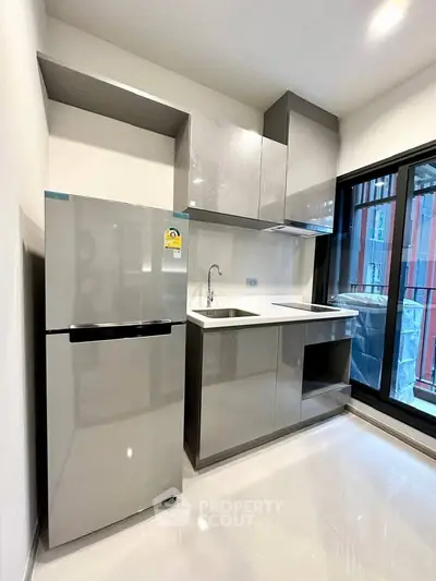 Modern kitchen with sleek cabinets and stainless steel fridge in a bright apartment.