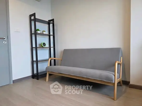 Modern minimalist living room with sleek gray sofa and stylish shelving unit.