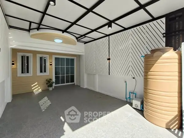 Modern covered outdoor area with stylish wall design and water storage tank.