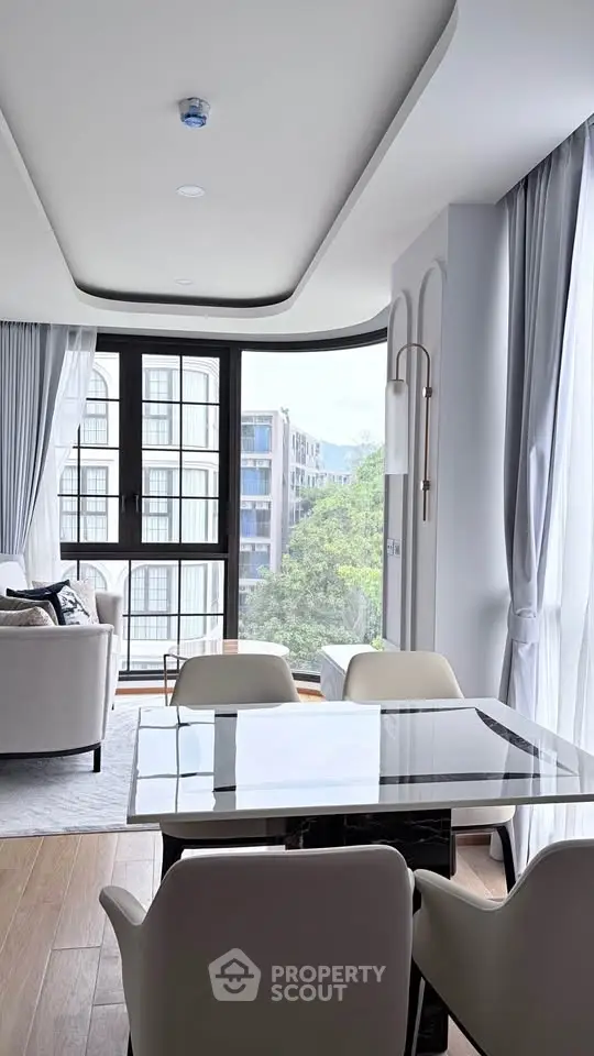Elegant modern living room with large windows and stylish dining area, offering a bright and inviting atmosphere.