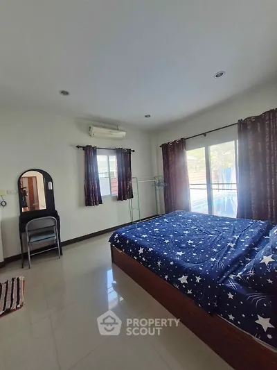 Spacious bedroom with starry bedding and natural light from large windows.