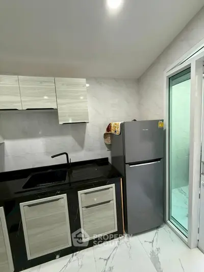 Modern kitchen with sleek cabinets and stainless steel fridge in a stylish apartment.