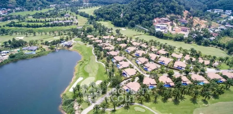 Stunning aerial view of luxurious lakeside villas surrounded by lush greenery and golf course.