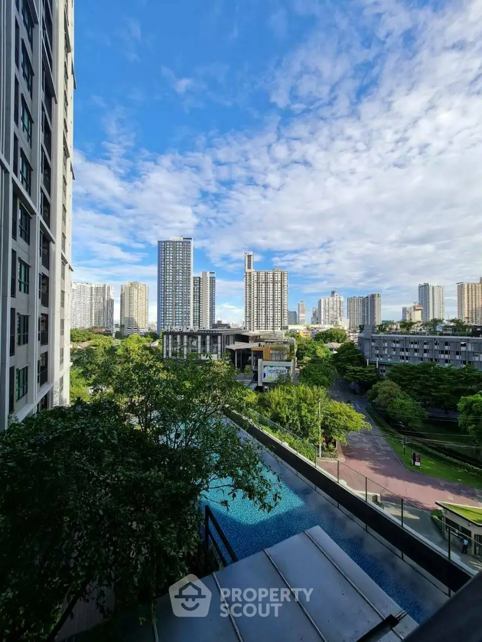 Stunning cityscape view from a high-rise building with lush greenery and a pool, perfect for urban living.