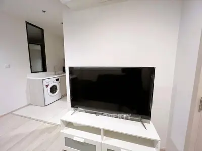 Modern apartment interior with sleek TV and washing machine in open layout.